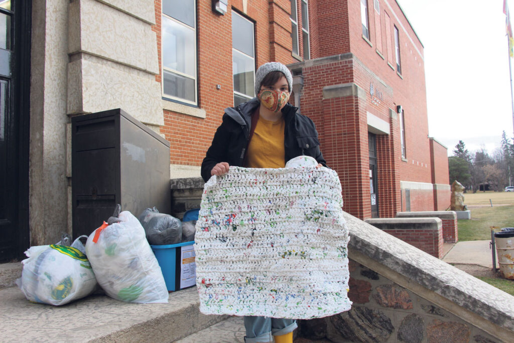 Student creating sleeping mats out of plastic bags for people